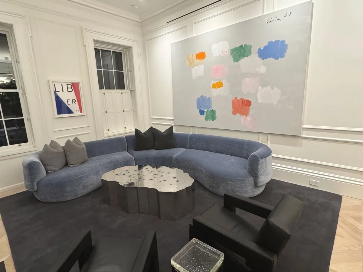 A blue velvet curved sectional in a white gallery-like living room