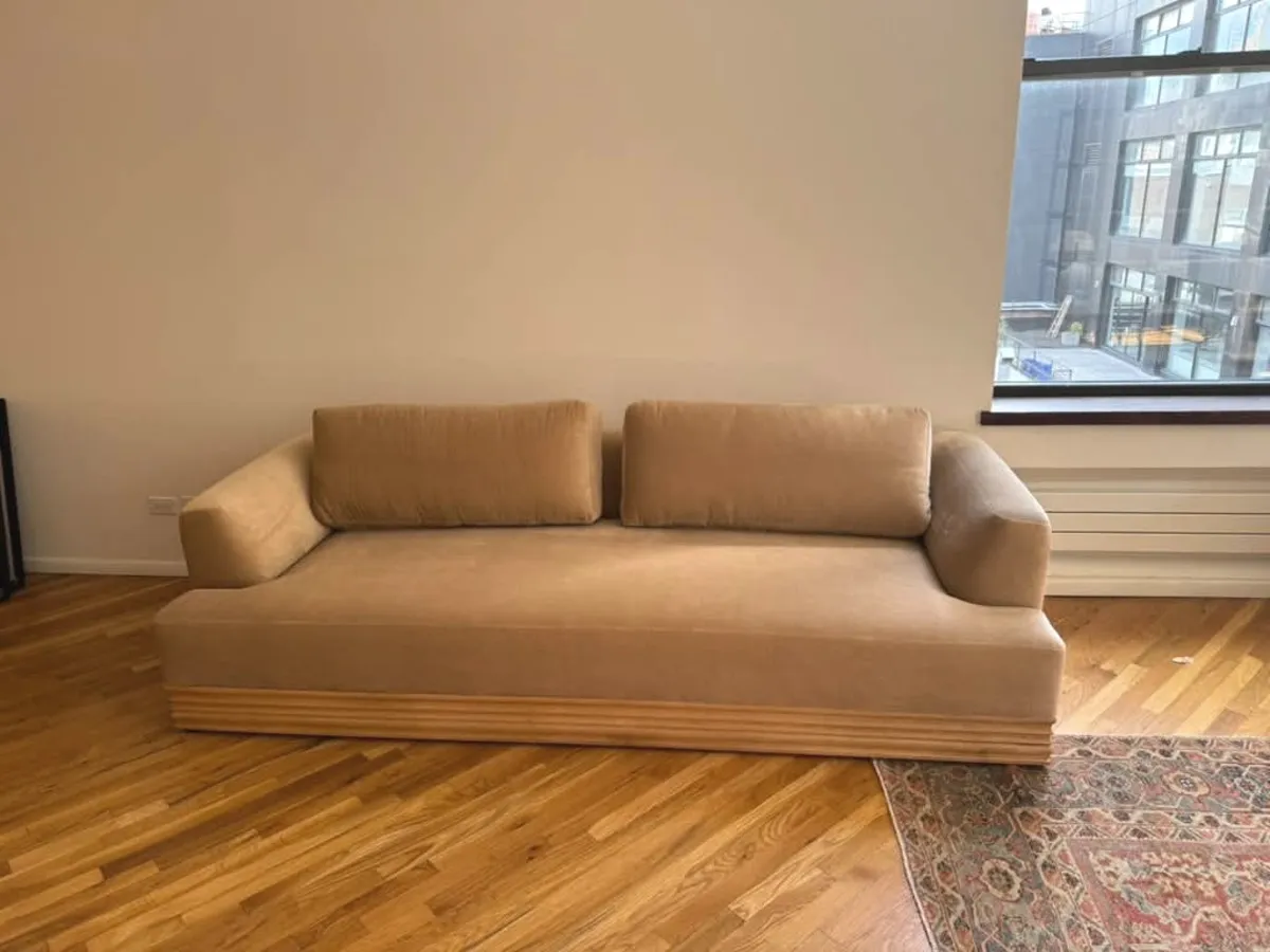 A camel velvet daybed on a wood floor in a quiet, bright room