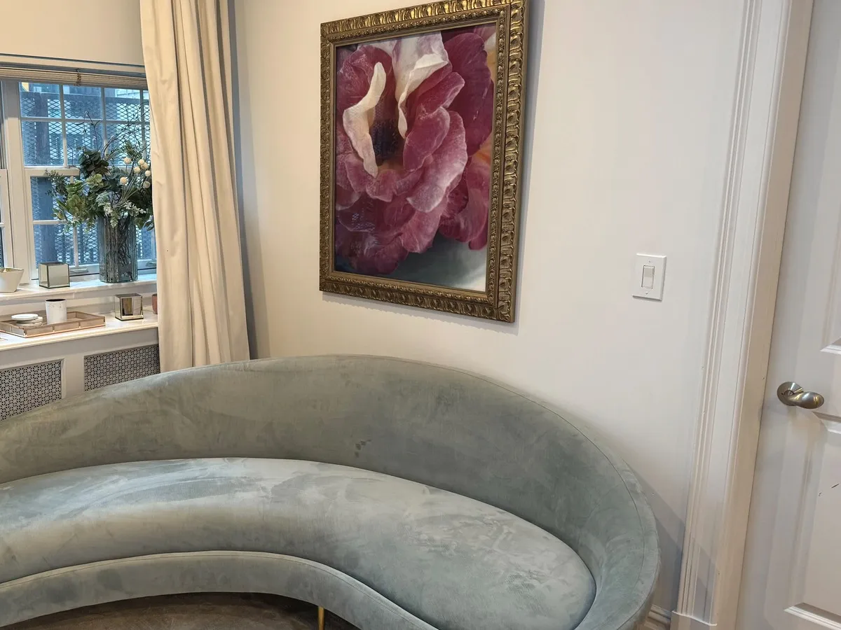 A celadon velvet kidney-shaped chaise beneath a gilt-framed peony painting