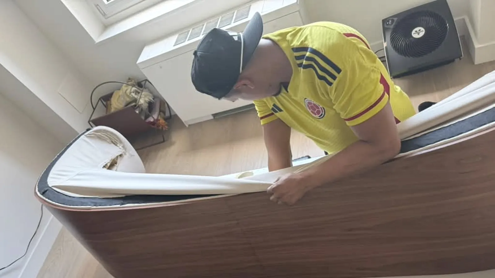 A member of the team easing upholstery back over the walnut frame of a curved sofa