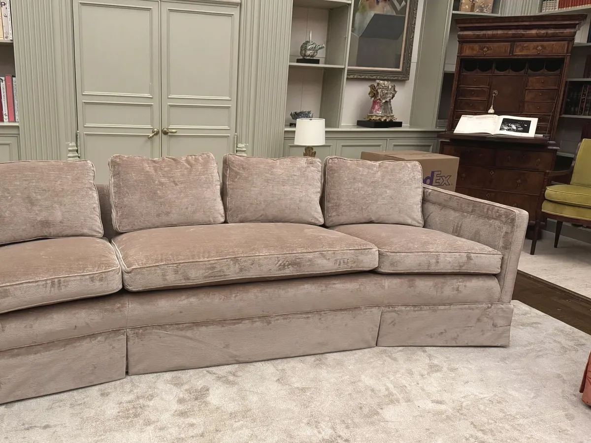 A pale velvet camelback sofa in a panelled library with built-in shelves