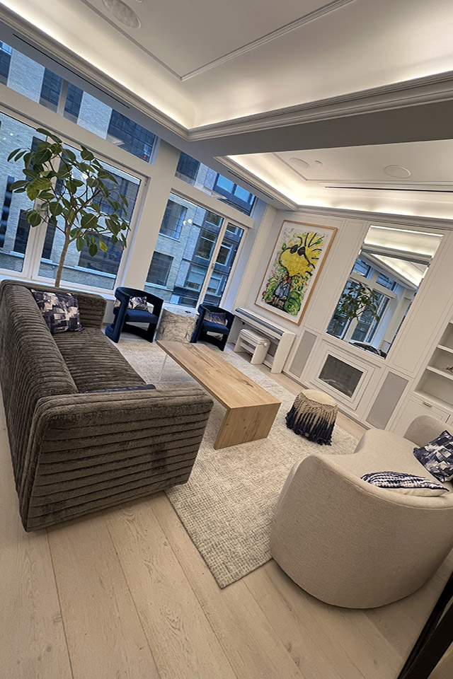 Cozy living room with grey-striped sofa, blue armchairs, fireplace, and built-in shelves—modern home decor.