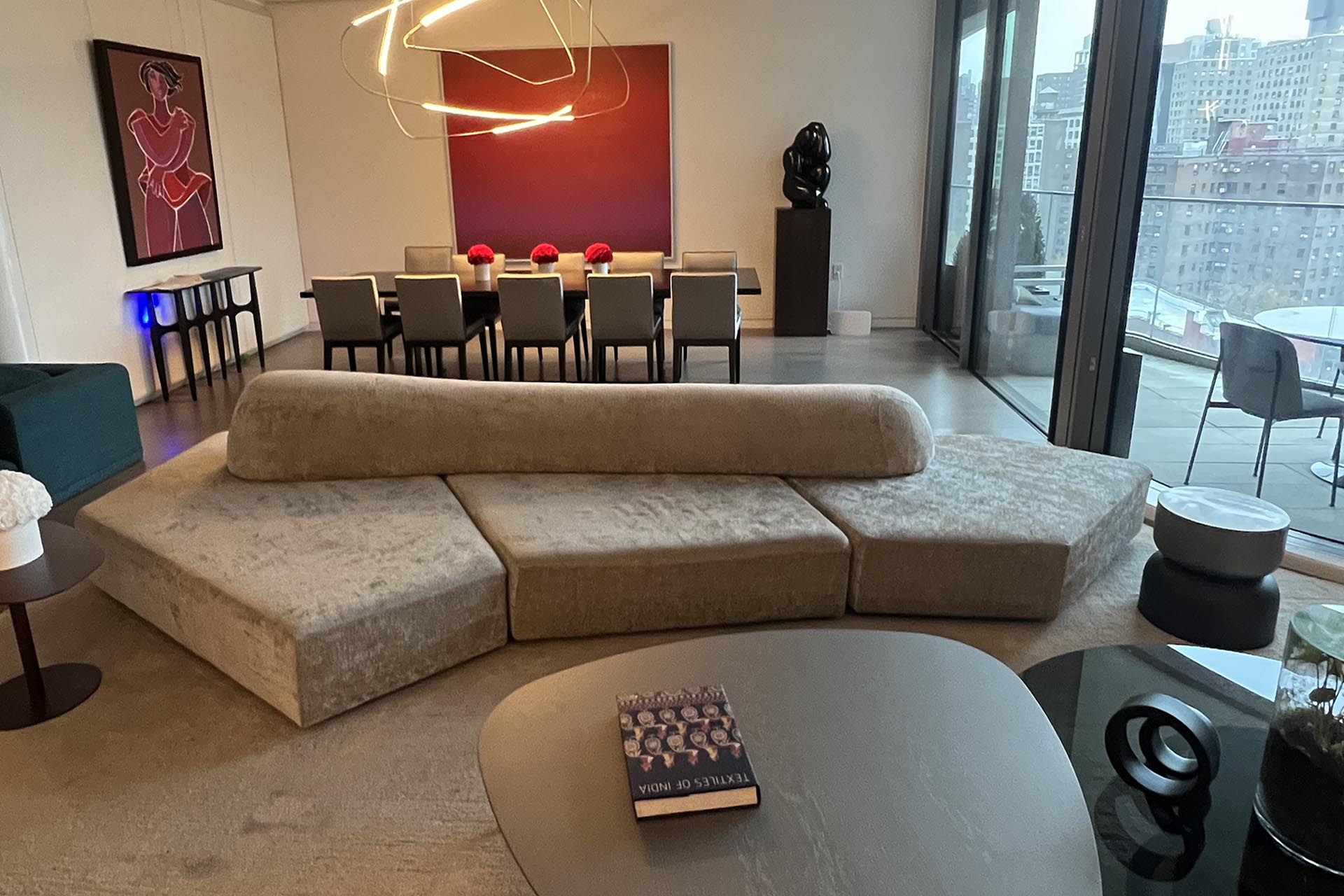 Modern sectional sofa in NYC apartment with luxury dining setup and city skyline view